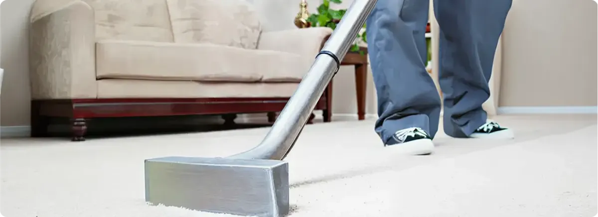 Carpet cleaning technician using a hot-water extraction wand on a light-colored carpet in a living room, Jacksonville, FL.